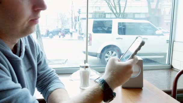 Mann schreibt SMS und surft mit Handy-App im Café — Stockvideo