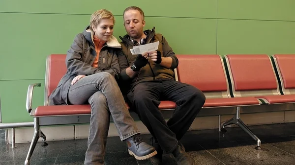 Pareja esperando en la terminal del aeropuerto con billetes — Foto de Stock