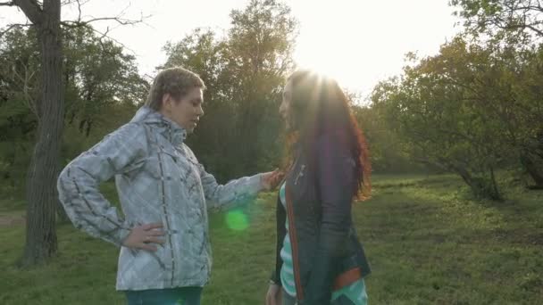 Två smiley flickor vänner talar i en grön park — Stockvideo