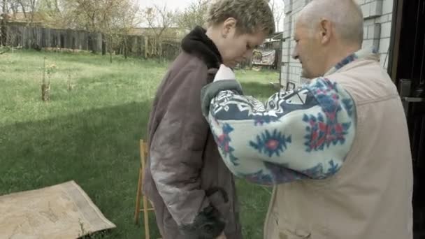 Velho homem sênior ajuda jovem mulher a limpar roupas — Vídeo de Stock