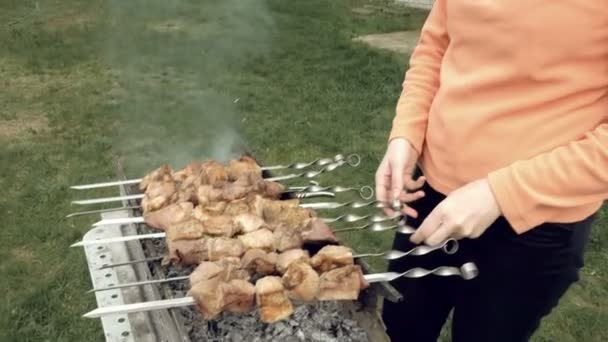 Girl cooks barbeque skewers with meat on brazier — Stock Video