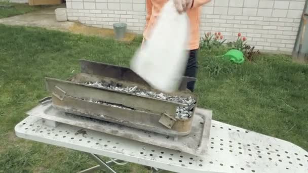 バーベキュー火鉢で石炭および燃え差しを吹く少女 — ストック動画