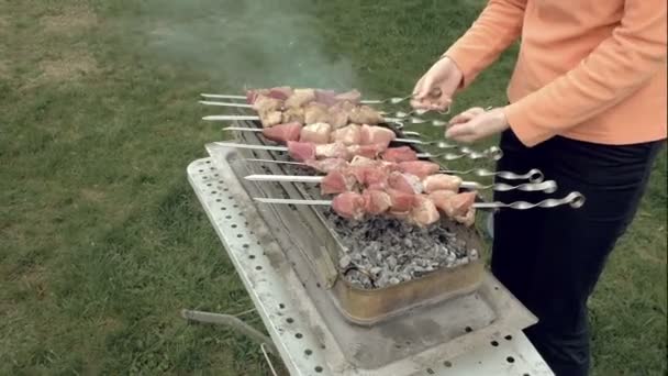 Meisje kookt barbecue spiesen met vlees op brazier — Stockvideo