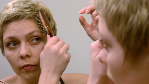 Hübsche blonde Frau kämmt und bürstet ihre Haare — Stockvideo
