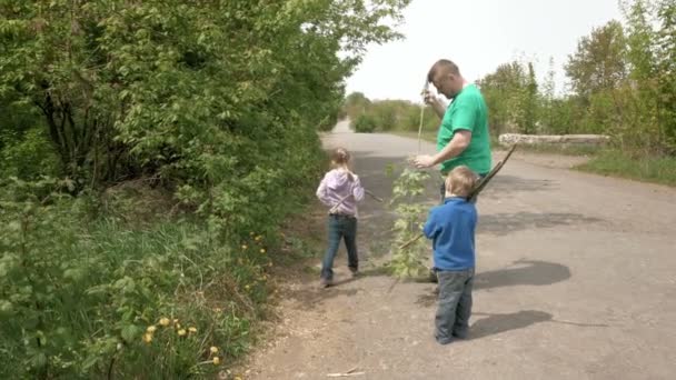 Vader en gelukkige kinderen spelen met stangen buitenshuis — Stockvideo