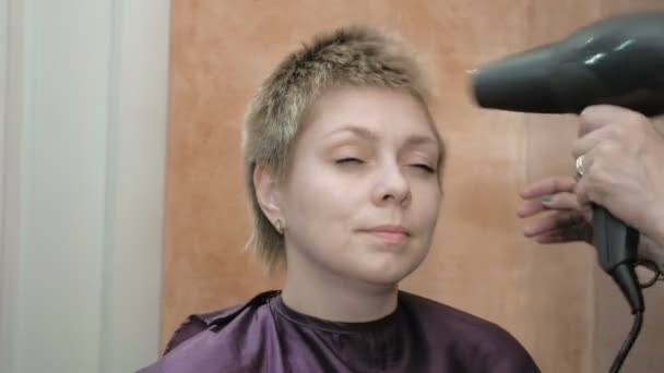 Friseur trocknet und stylt kurze Haare blonden Kopf — Stockvideo
