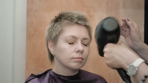 Hairdresser dries and styles short hair blond head — Stock Video