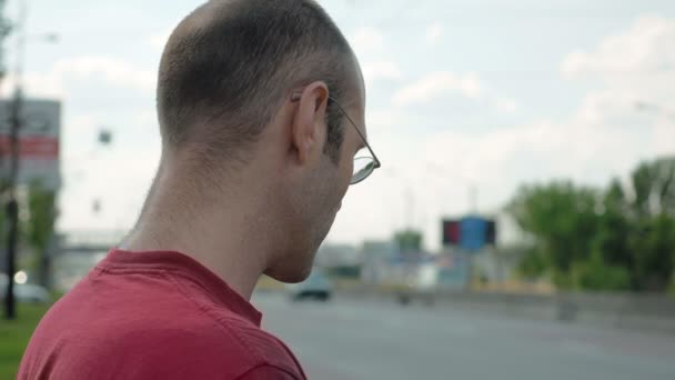 Человек стоит на обочине городской дороги — стоковое видео