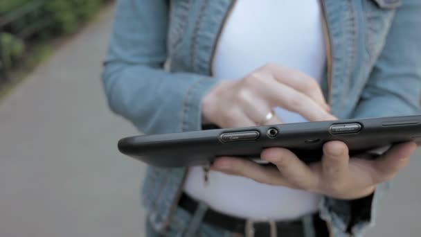 Kvinnan skriver texter på tablet pc promenader utomhus — Stockvideo