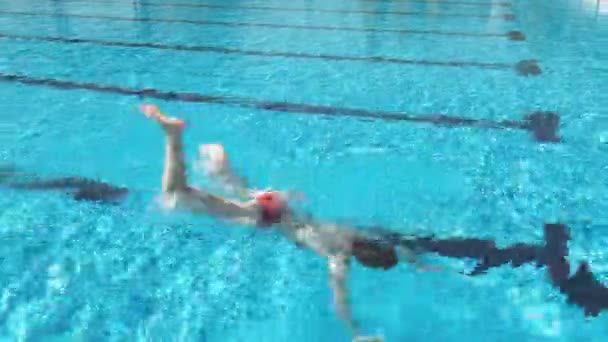 Mujer buceando bajo el agua azul en una piscina — Vídeo de stock