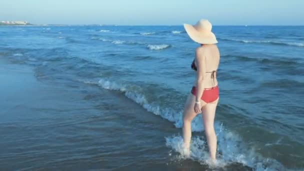 Mujer en bikini con sombrero de sol de paja caminando playa — Vídeos de Stock