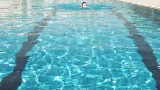 Mujer está nadando en una piscina en un día de verano brillante — Vídeo de stock