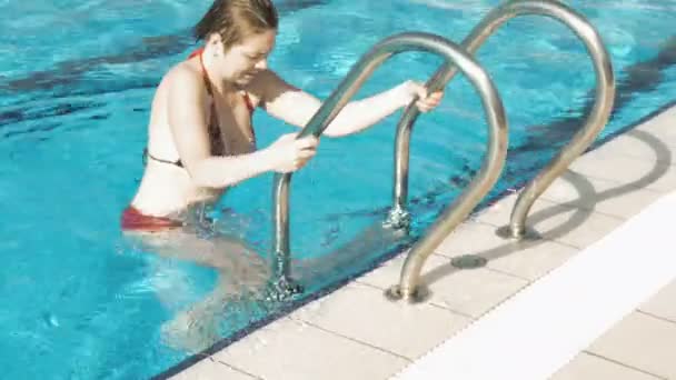 Женщина в красном бикини выходит из бассейна — стоковое видео