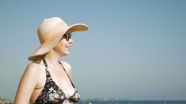 Donna in piedi sulla spiaggia con il suo cappello fantasia — Video Stock