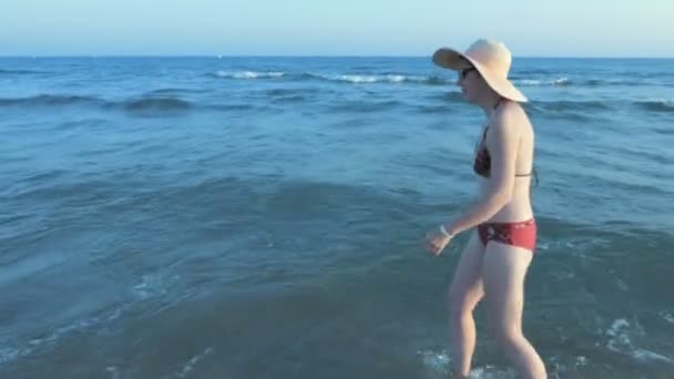 Feminino perde seu chapéu de sol andando ao lado do mar — Vídeo de Stock