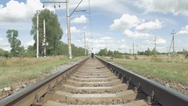 Homem caminhando ao longo trilhos ferroviários em direção à câmera — Vídeo de Stock