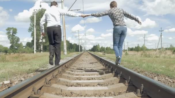 Man en vrouw hand in hand wandelen langs spoorwegen — Stockvideo