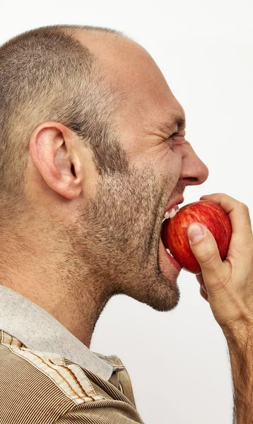 Homem morde maçã vermelha — Fotografia de Stock