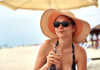 Beautiful girl in wide-brimmed hat drinking champagne clipart