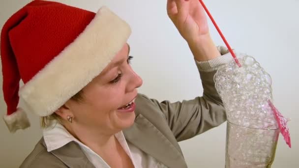 Дівчина в червоному різдвяному капелюсі дме бульбашки весело — стокове відео