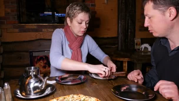 Молодая пара мужчина и женщина едят пиццу в кафе — стоковое видео