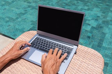 Parmaklar dizüstü bilgisayarda yazıyor. Havuz kenarında serbest çalışıyorum. Havuz kenarında serbest çalışıyorum.. 