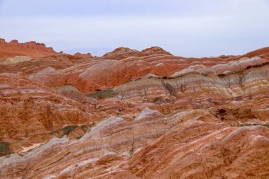 Gökkuşağı Dağı 'nın muhteşem manzarası ve gün batımında mavi gökyüzü arkaplanı. Zhangye Danxia National Geopark, Gansu, Çin. Renkli manzara, gökkuşağı tepeleri, sıra dışı renkli kayalar, kumtaşı erozyonu.