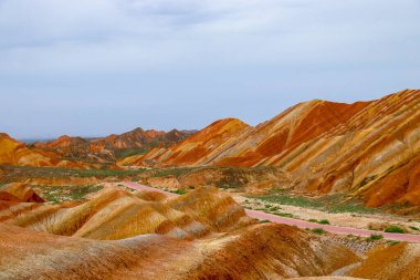 Gökkuşağı Dağı 'nın muhteşem manzarası ve gün batımında mavi gökyüzü arkaplanı. Zhangye Danxia National Geopark, Gansu, Çin. Renkli manzara, gökkuşağı tepeleri, sıra dışı renkli kayalar, kumtaşı erozyonu.