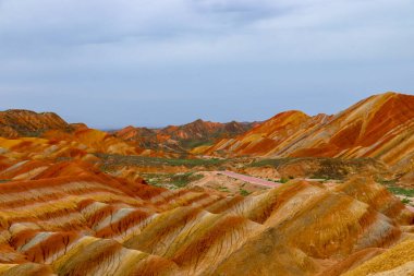 Gökkuşağı Dağı 'nın muhteşem manzarası ve gün batımında mavi gökyüzü arkaplanı. Zhangye Danxia National Geopark, Gansu, Çin. Renkli manzara, gökkuşağı tepeleri, sıra dışı renkli kayalar, kumtaşı erozyonu.