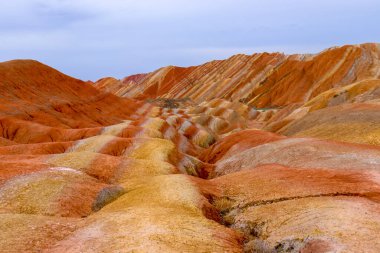 Gökkuşağı Dağı 'nın muhteşem manzarası ve gün batımında mavi gökyüzü arkaplanı. Zhangye Danxia National Geopark, Gansu, Çin. Renkli manzara, gökkuşağı tepeleri, sıra dışı renkli kayalar, kumtaşı erozyonu.
