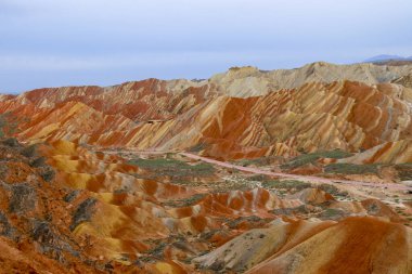 Gökkuşağı Dağı 'nın muhteşem manzarası ve gün batımında mavi gökyüzü arkaplanı. Zhangye Danxia National Geopark, Gansu, Çin. Renkli manzara, gökkuşağı tepeleri, sıra dışı renkli kayalar, kumtaşı erozyonu.