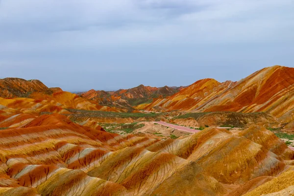 Gökkuşağı Dağı 'nın muhteşem manzarası ve gün batımında mavi gökyüzü arkaplanı. Zhangye Danxia National Geopark, Gansu, Çin. Renkli manzara, gökkuşağı tepeleri, sıra dışı renkli kayalar, kumtaşı erozyonu.