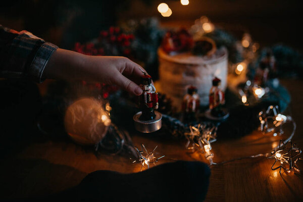 close up of hand holding christmas decoration, candles and garland 