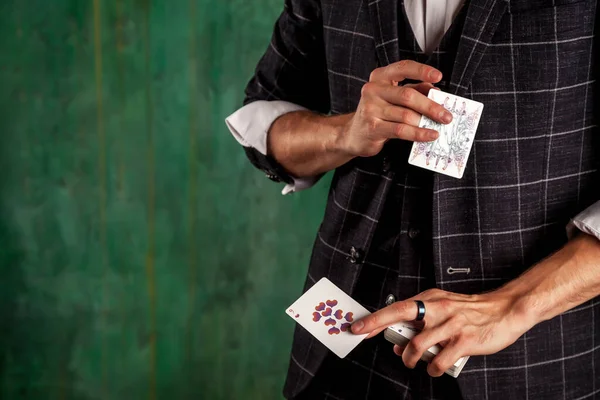 ギャンブルカードを持つ若い男のクローズアップ手 ハンサムな男はトランプでトリックを示しています 緑のテクスチャの背景に魔術師の巧妙な手 エンターテインメントと趣味の概念 スペースのコピー — ストック写真