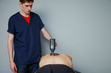 Spor salonunun tıbbi odasında spor perküsyon masajı. Masör masaj egzersizleri yapıyor. Spor vücut masajı için perküsyon terapisi. Spor sakatlıklarının rehabilitasyonu. Boşluğu kopyala