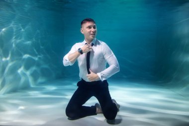 Şirin başarılı genç iş adamı kravatını düzeltiyor ve suya bakıyor. Duygusal adam gölette direktördür. Çalışma saatleri kavramı ve ofiste iş kararları. Boşluğu kopyala