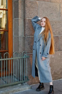 Gri montlu şık, genç ve şık bir kadın sokakta yürüyor. Gülümseyen, mutlu ve maksatlı kadınlar için sonbahar modası. Tarz, moda, güzellik ve başarı hedefleri. Boşluğu kopyala