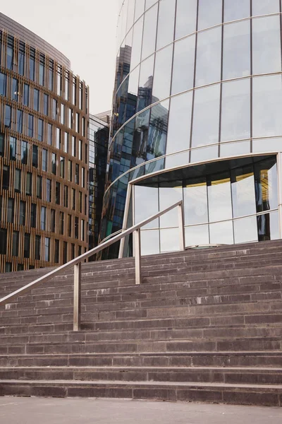 Concrete steps lead to business building in business district. Stairs to facades of skyscrapers in background. Architecture of building in business district of metropolis. Copyright space