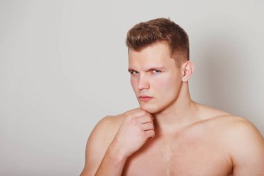 Işık yalıtılmış arka planda atletik yapılı yakışıklı genç bir adamın portresi. Yakışıklı, kaslı, kaslı bir adam. Spor anlayışı, beden eğitimi, fitness ve sağlıklı yaşam tarzı. Boşluğu kopyala