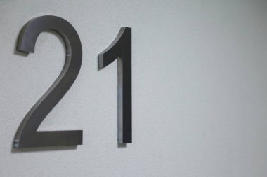 Doku aydınlatma duvarında yirmi bir numara, 2021 yılını simgeliyor. Krom numaralar, yüzeysel beyaz renk gradyan zemin üzerinde 21. İki ve bir numaralı tek renkli arka plan. Boşluğu kopyala