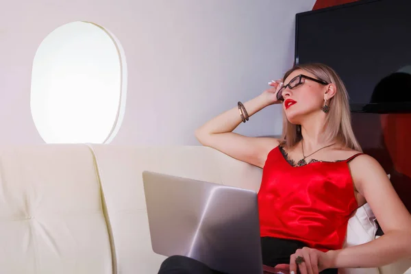 Cute young businesswoman resting flying in luxury private jet. Business woman in airplane first class seat during trip. Concept quality of passenger service in aviation industry, travel at highest