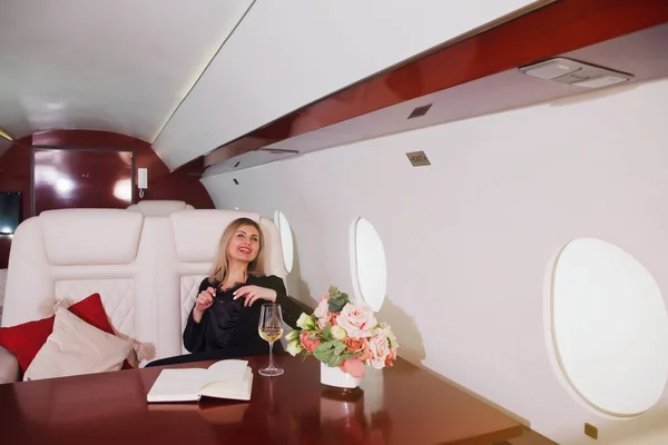 Cute young businesswoman working on laptop in private jet. Business woman in airplane first class seat during trip. Concept quality of passenger service in aviation industry, luxury travel at highest
