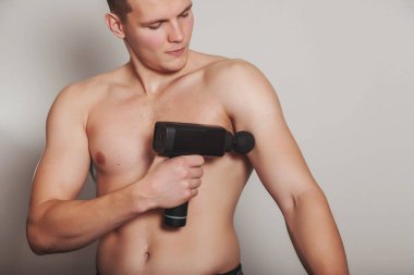 Sporcu spor salonunun tıbbi ofisinde silah şok masajı yapıyor. Sporcu ev masajı egzersizleri. Vücut masajı için perküsyon terapisi. Yara rehabilitasyonu kavramı. Boşluğu kopyala