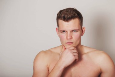 Işık yalıtılmış arka planda atletik yapılı yakışıklı genç bir adamın portresi. Yakışıklı, kaslı, kaslı bir adam. Spor anlayışı, beden eğitimi, fitness ve sağlıklı yaşam tarzı. Boşluğu kopyala