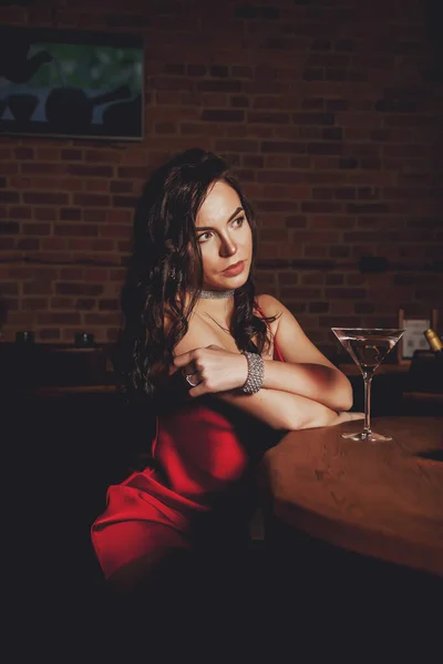 在黑暗的内部背景餐厅里 年轻性感 时尚的女人穿着亮晶晶的红色连衣裙 照片广告行业的漂亮女性形象 广告照片的概念 复制空间 — 图库照片