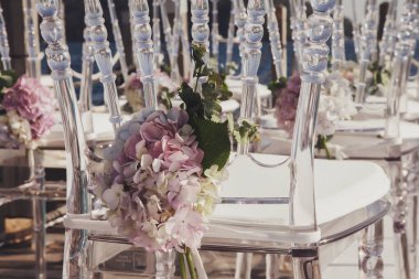 Restoranda panoramik deniz manzaralı taze çiçeklerle süslenmiş beyaz düğün sandalyeleri. Etkinlikler için lüks tasarım. Kutlamalar ve törenler için arka plan. Yaratıcılık için mükemmel bir görüntü. Boşluğu kopyala