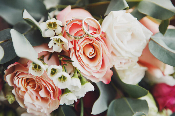 Close-up of wedding bouquet and gold wedding rings. Background for wedding celebrations and marriage ceremonies. Luxury design for events. Perfect image for creativity. Copy space site