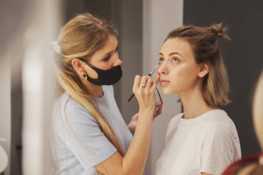 Kadın makyaj sanatçısı güzellik salonunda güzel bir kadın yaratıyor. Dahili salondaki müşteri hizmetleri inanılmaz bir imaj yaratıyor. Makyaj yaratma sihirbazı. Ölçülü tatmin kavramı. Boşluğu kopyala