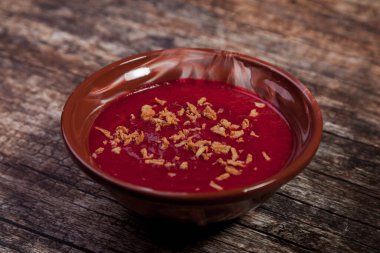 Sebzeli soğuk pancar kremalı çorba ve ahşap arka planda soğan cipsi. Kahverengi tabakta soğanlı geleneksel kremalı borş çorbası. Vejetaryen çorbası borş domates, havuç, zeytinyağı. Boşluğu kopyala