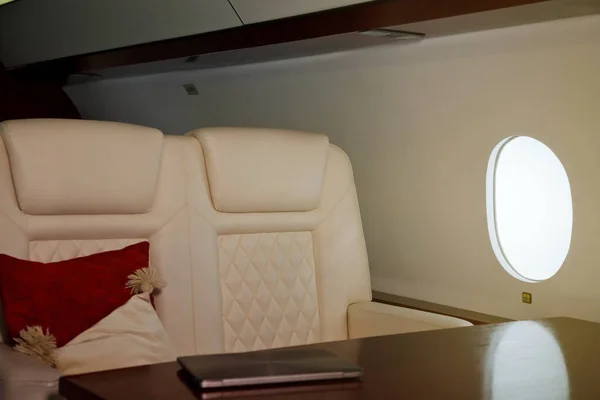 Laptop on work table of luxury interior in private jet. Modern and comfortable business airplane with decor. Concept of passenger service quality in aviation industry, at highest